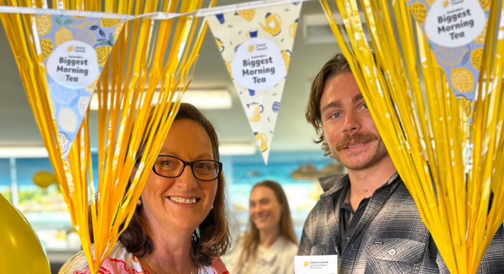staff posing behind balloons and streamers for biggest morning tea