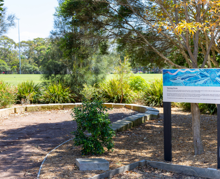 Sandstone edged yarning circle with green foliage surrounding it