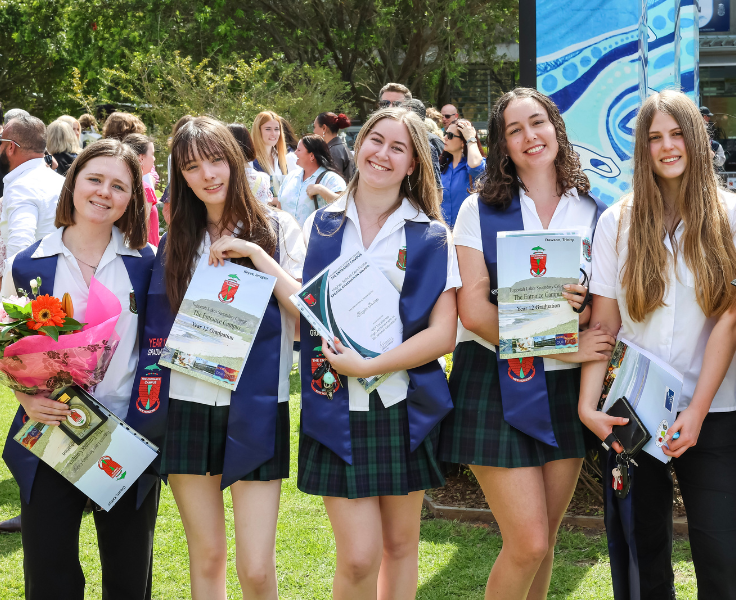 Students holding their graduation awards outside
