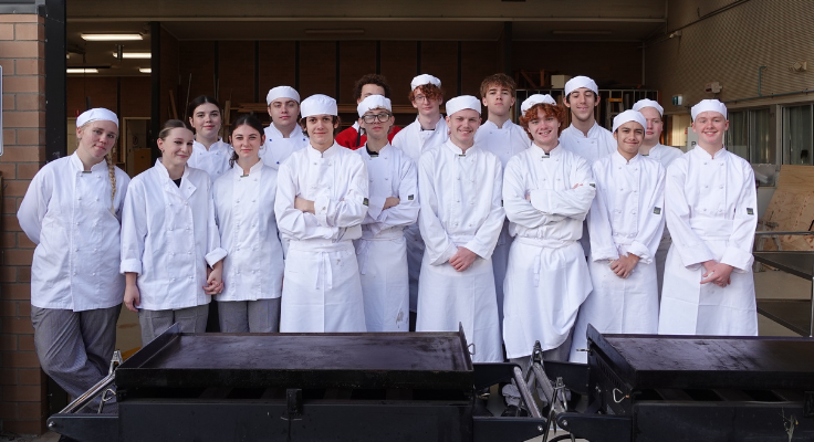 a big group of students all wearing chef uniforms