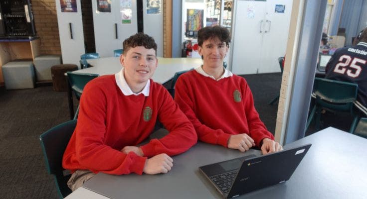 2 students with a laptop on a desk in the library