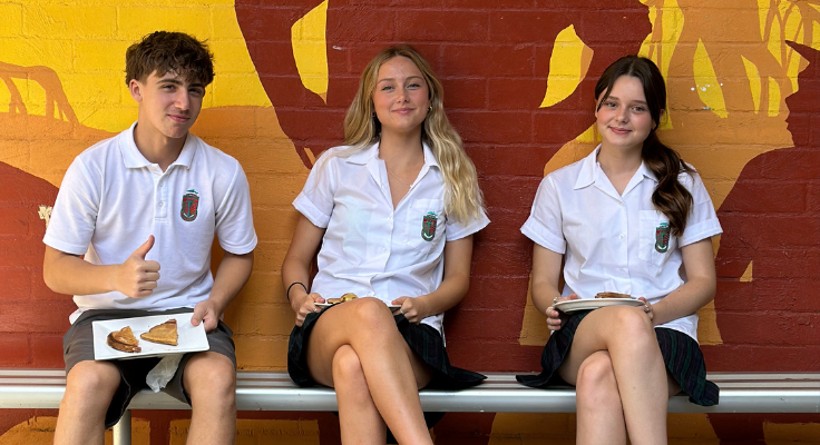 students sitting on a bench with a mural behind them