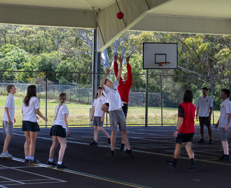 Group of students playing basketball under a recently refurbished
