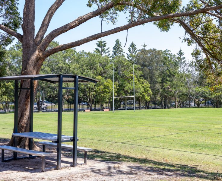Lush green oval with football goals in the background with shaded table in foreground