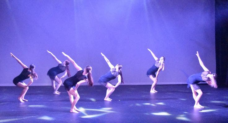 Six dancers reaching to the sky while on stage