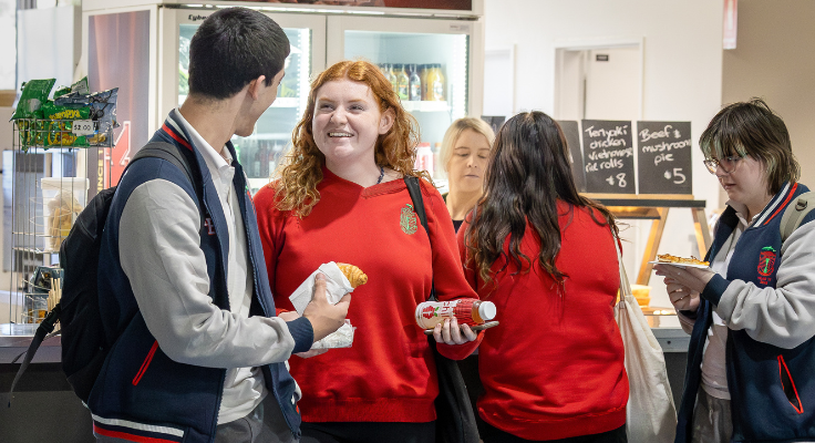 Students smiling at cafeteria holding food
